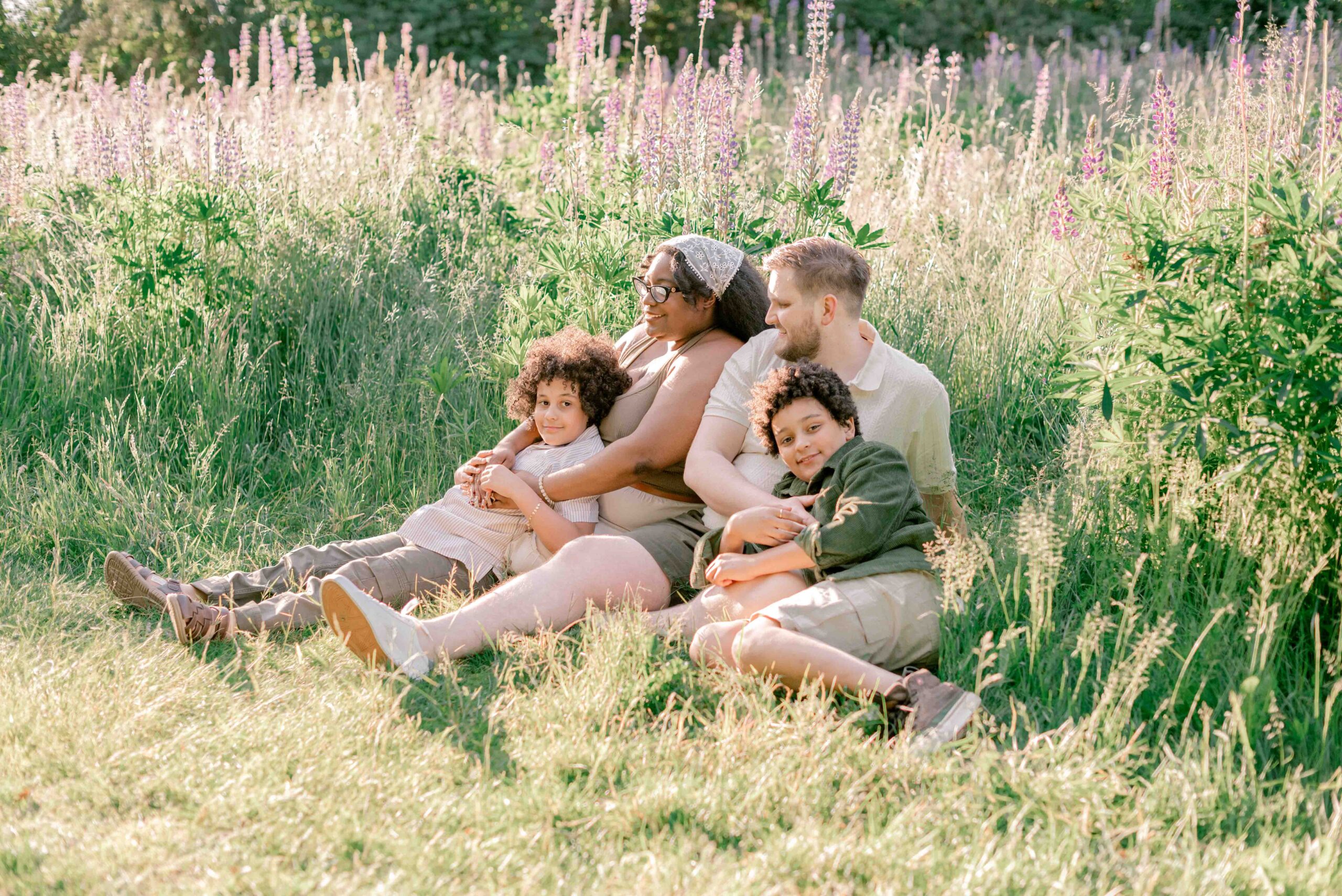 family of four sit and play in the lupine field in family photoshoot at Discovery Park