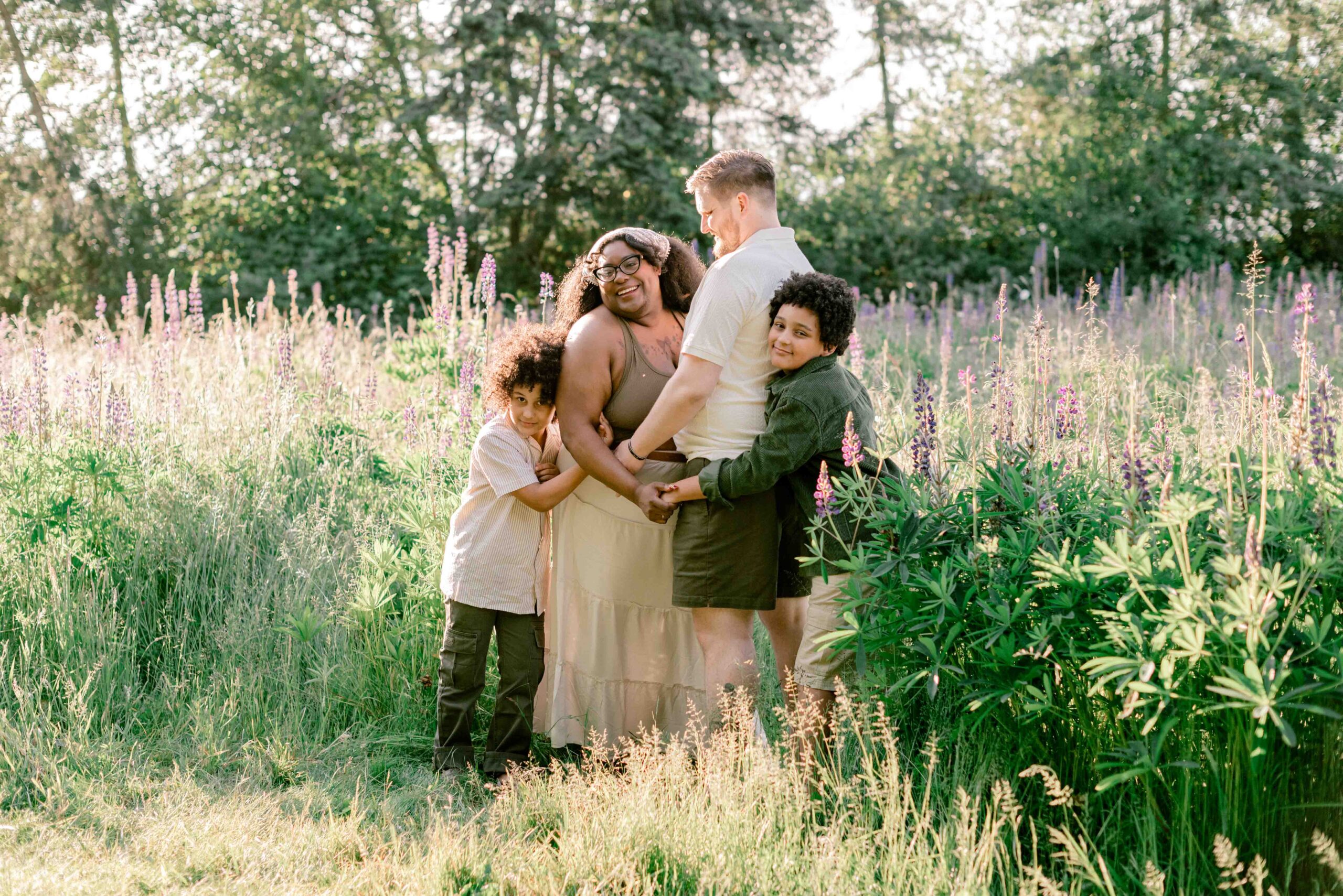 family of four pose in front of Lupine field in family photoshoot at Discovery Park